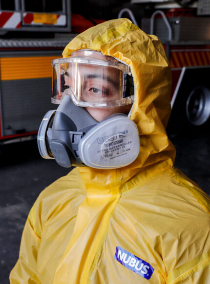Operario industrial equipado con traje de protección amarillo marca Nubus, gafas de seguridad estancas y la máscara de medio rostro UCU6200RM talle M con filtros de partículas UCU0511R instalados.