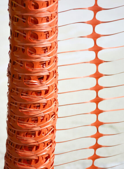 Plano detalle de la estructura plástica calada y el entramado flexible de la malla de advertencia naranja UCU0500PV en posición vertical.