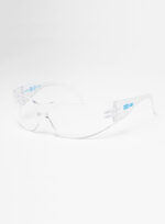 Vista de perfil en tres cuartos del protector ocular monolente transparente UCU111B sobre fondo blanco, mostrando sus patillas ergonómicas y el logo de la marca impreso en azul.