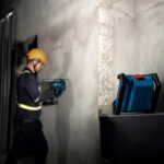 Linterna Bosch GLI 18V-1500 colocada en altura sobre una estructura metálica iluminando a un técnico en obra.