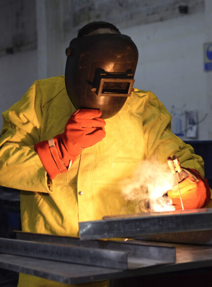 Operario industrial utilizando la campera de descarne amarilla durante tareas de soldadura.