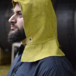 Operario posando de perfil utilizando gorro de cuero descarne amarillo con nuquera De Pascale 96102.