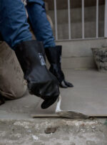 Albañil colocando mezcla con una cuchara de albañil utilizando los guantes de látex negro DP DPS71395.