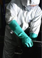Operario con traje de protección utilizando los guantes de nitrilo pesado DP DPS43484 en la industria química.
