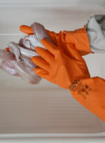 Operario con guantes de nitrilo naranja DP manipulando filetes de pescado fresco en planta alimenticia.